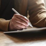 Close-up view of man working on his project while using tablet in his comfortable office